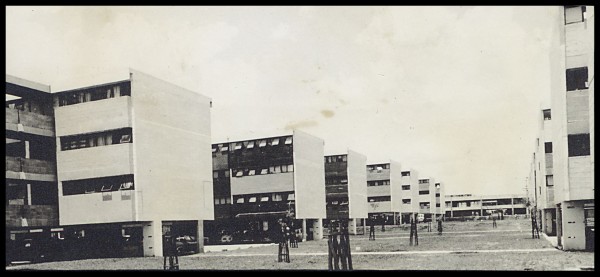 Descrição gerada por inteligência artificial: Imagem de prédios, janelas, grama, céu